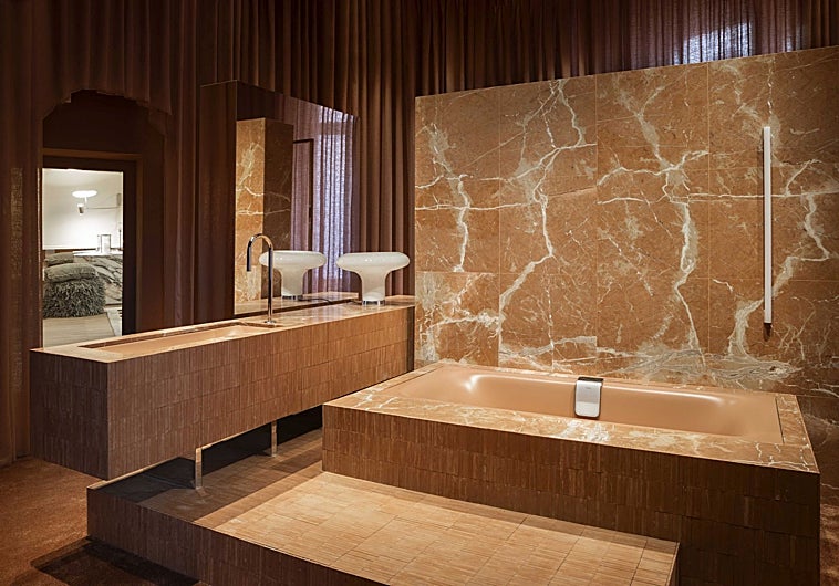 Imagen principal - Baño de Kaldewei por IVL Isabel López Vilalta, con sus piedras en primer plano y la gama cromática ganadora, en tonos tierra; el lobby de Sandra Antón, con sofá en curva, pared entelada y luminaria decorativa, y el espacio Mapei por Cano y Escario Arquitectura, con más curvas y otro de los techos protagonistas de la feria.