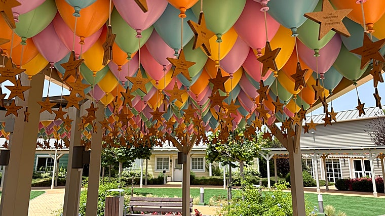 A lo largo de una pérgola se colocan unos globos de los que cuelgan una estrella con el nombre de cada niño que pasa por Dreams