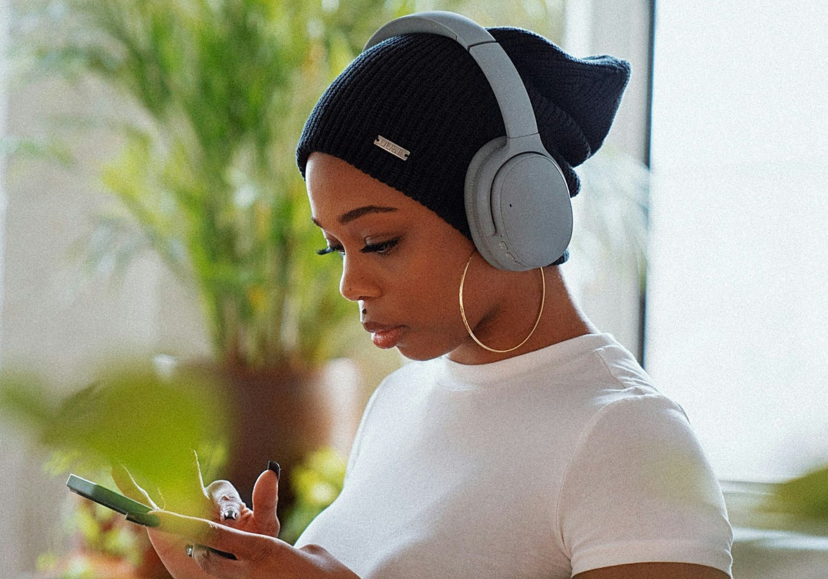 Una chica con auriculares mira el móvil
