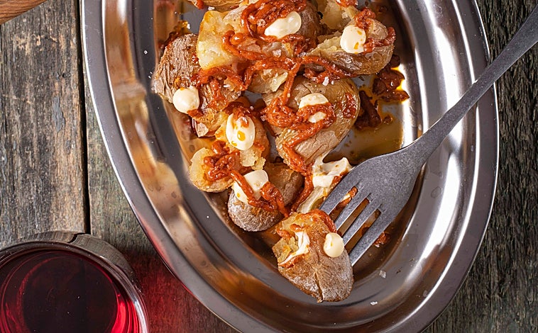 Imagen principal - Sobre estas líneas, arriba, las patatas bravas. Abajo, a la izquierda, la ensaladilla 'golpeá' de gambón. A la derecha, Daniel Montes y Ana Romero, en la puerta de La Taberna del Lobo de Malasaña