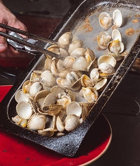 Imagen secundaria 2 - Sobre estas líneas, algunos de los platos de Moments. Las conchas abiertas en el josper son una de sus especialidades. Arriba, los mejillones 'cabreaos'. Abajo a la derecha, los berberechos. Al lado, una de la decena de cocas que ofrecen