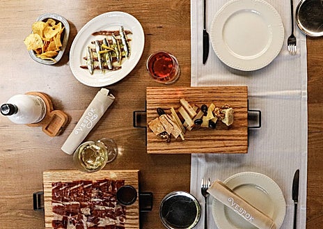 Imagen secundaria 1 - Sobre estas líneas, la terraza de El Rincón de Vespok, en la urbanización Puerta de Hierro de Madrid. Abajo, alguna de sus propuestas de picoteo y la tarta de quesos ahumados para dos que hornean al momento