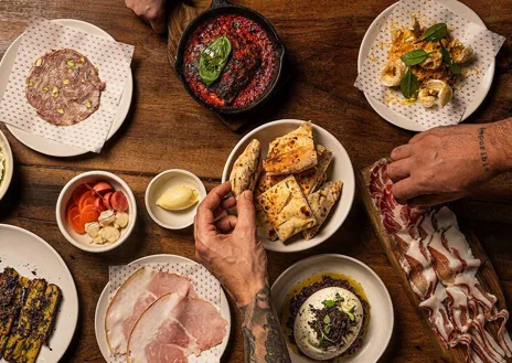 Imagen secundaria 1 - Sobre estas líneas, el local de Sartoria Panatieri en Eixample. Abajo, a la izquierda algunos de los platos que acompañan su oferta de pizzas. A la derecha, su horno de leña