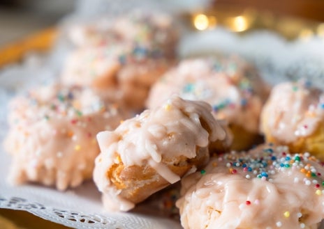 Imagen secundaria 1 - Sobre estas líneas, pasteleros de Casa Mira haciendo su versión de rosquilla infantil con chocolate blanco, frambuesa y petazetas. Abajo, a la izquierda, rosquillas de nubes de azúcar de El Pozo. A la derecha, cartel de la campaña Madridulce con las cinco versiones de rosquillas de San Isidro para niños de las pastelerías centenarias de Madrid