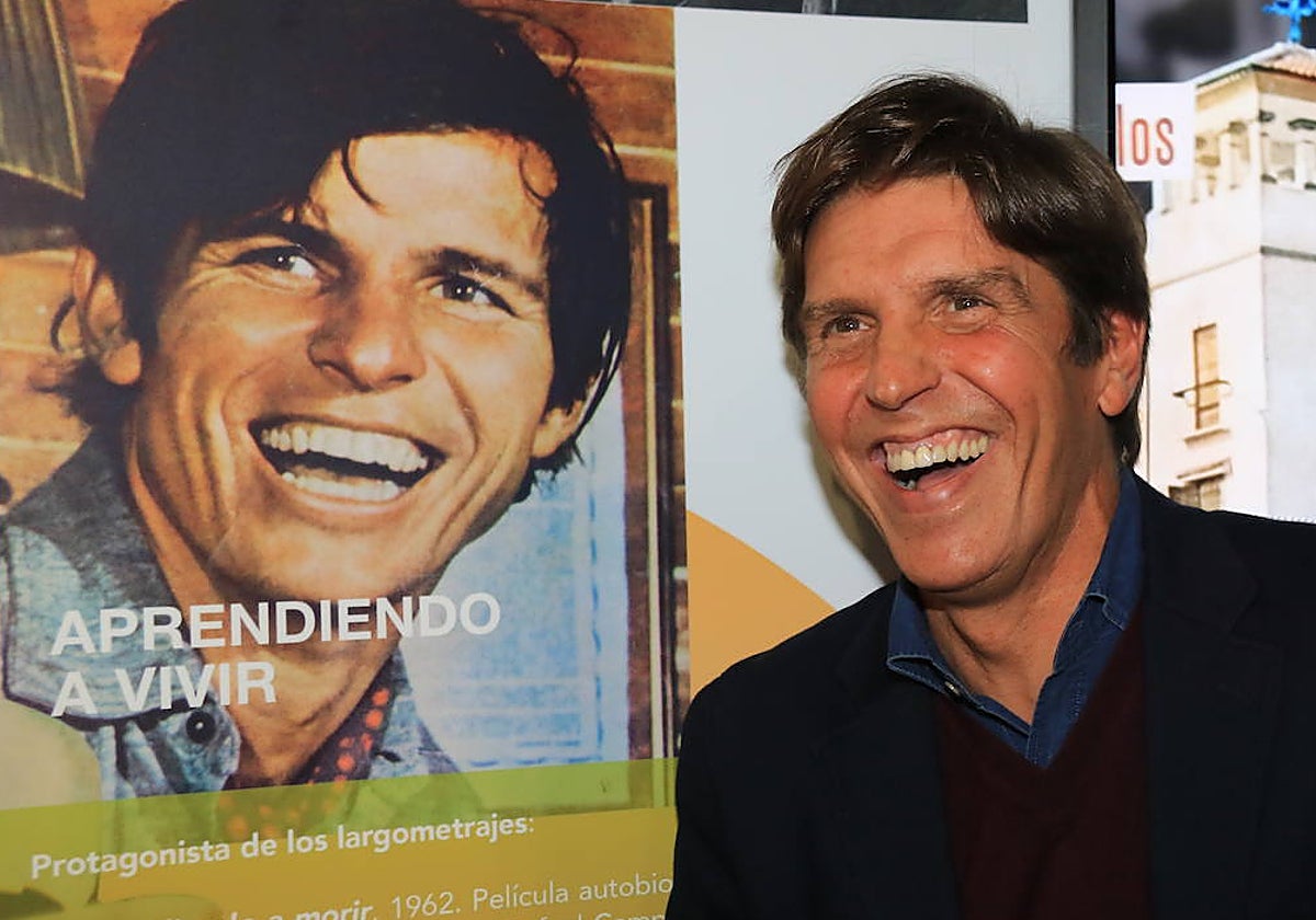 Manuel Díaz posa frente a un cartel en el que aparece su padre de joven