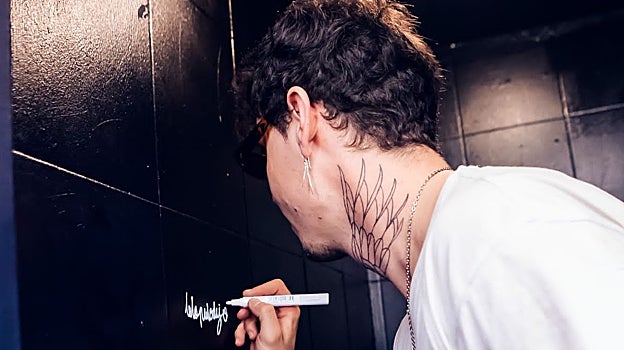 Alex Brooking pintando una frase en un baño