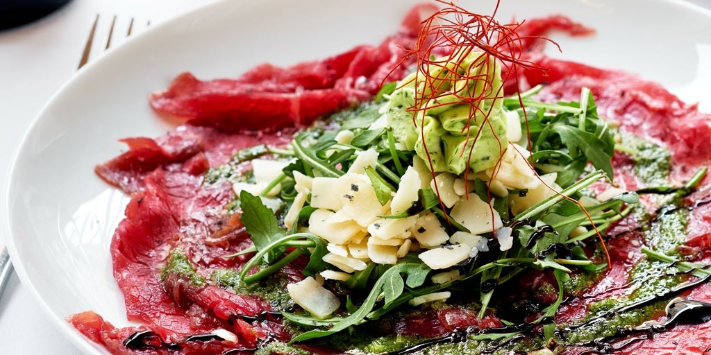 Tostada de carpaccio, hummus de remolacha, rúcula y brotes de soja