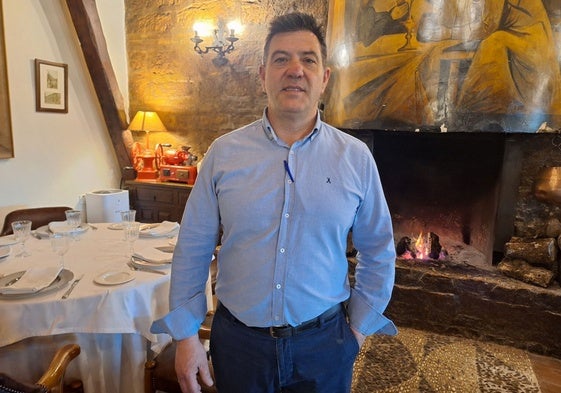 Raúl Márquez, jefe de sala y propietario del restaurante Las Camachas, de Montilla, ante la chimenea sobre la que están inmortalizadas las célebres brujas Las Camachas