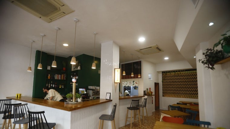 Vista general del bar, con la barra y la cocina al fondo