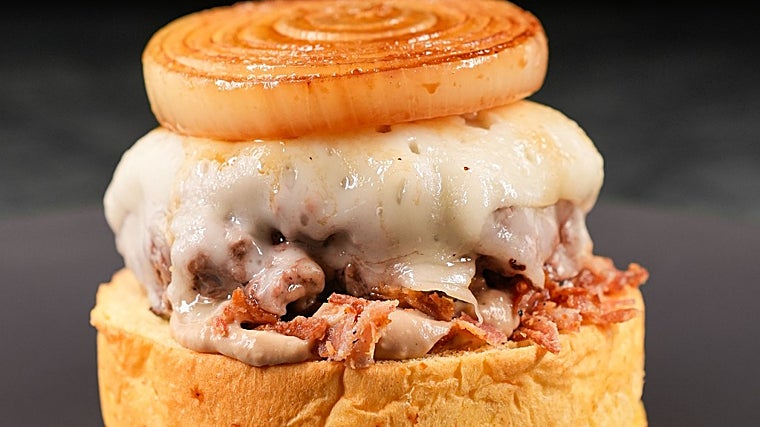 'La Reina' se compone de pan brioche, queso tierno de cabra, taco de cebolla marinado, bacon bits y salsa de crema de foie