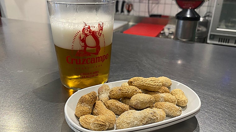 Cerveza Cruzcampo en vaso de sidra con cacahuetes