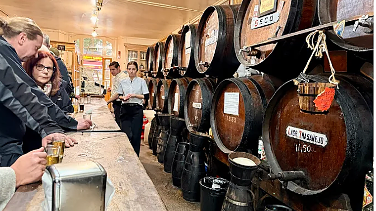 Tras su barra, reinan los toneles con vinos de producción propia