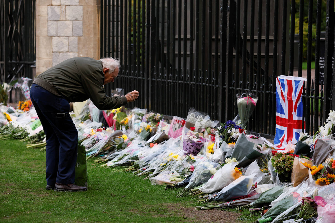 Un hombre fotografía las flores y notas que los ciudadanos han dejado en la valla del Palacio