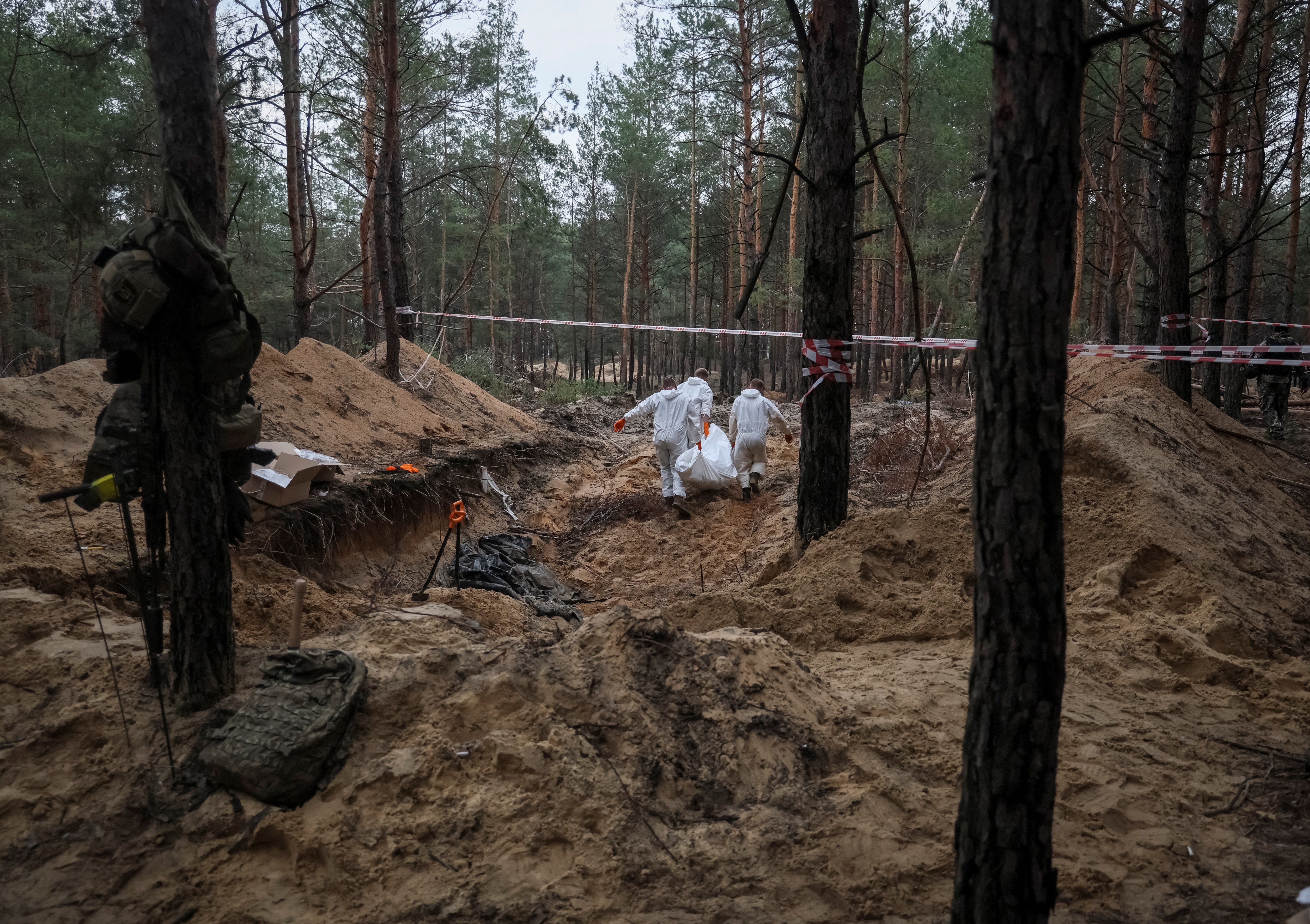 Varios trabajadores se encargan de recoger los cadáveres de compatriotas ucranianos tras el ataque ruso a Izium