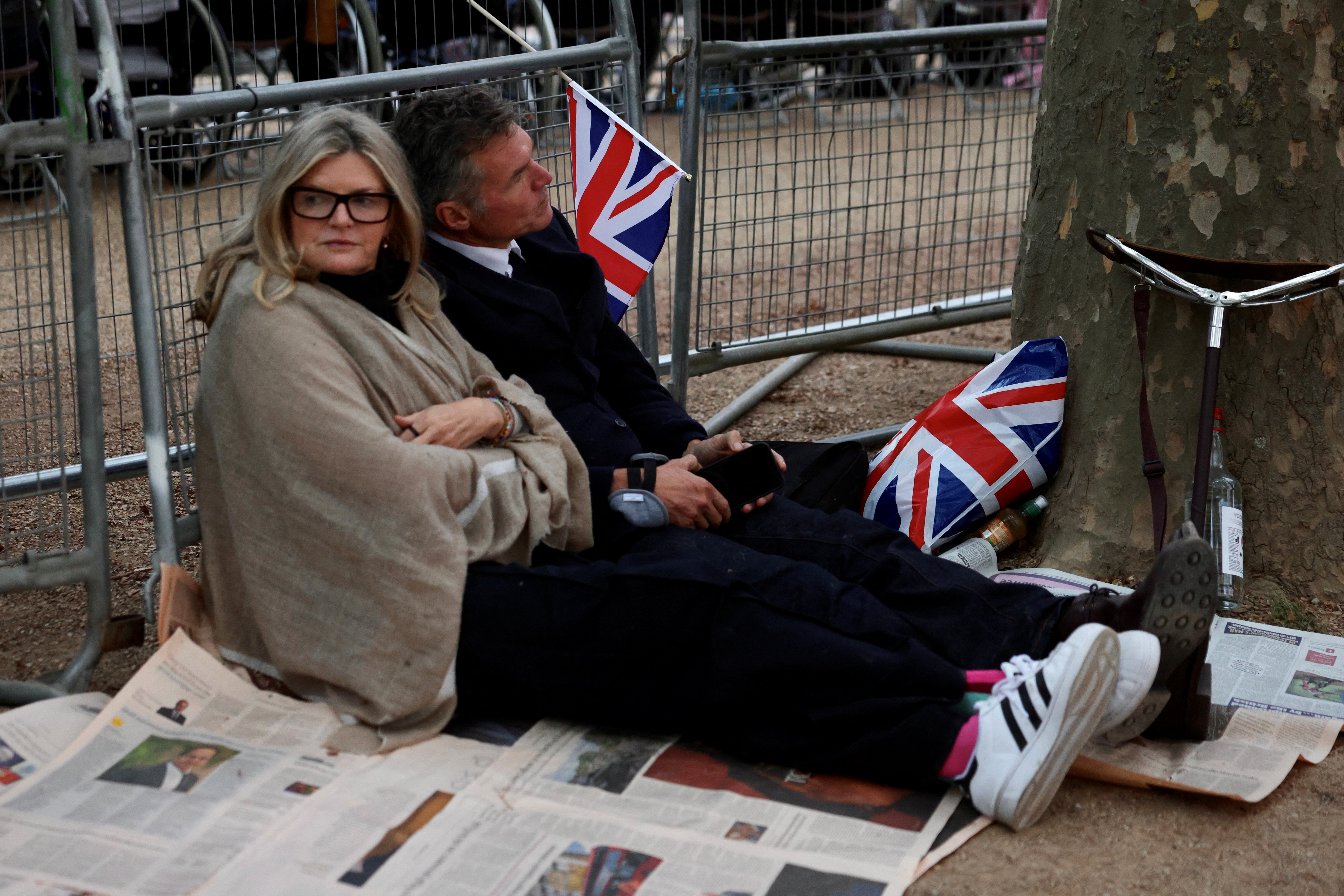Una pareja espera sentada en The Mall, en Londres, el paso de la procesión fúnebre de Isabel II.