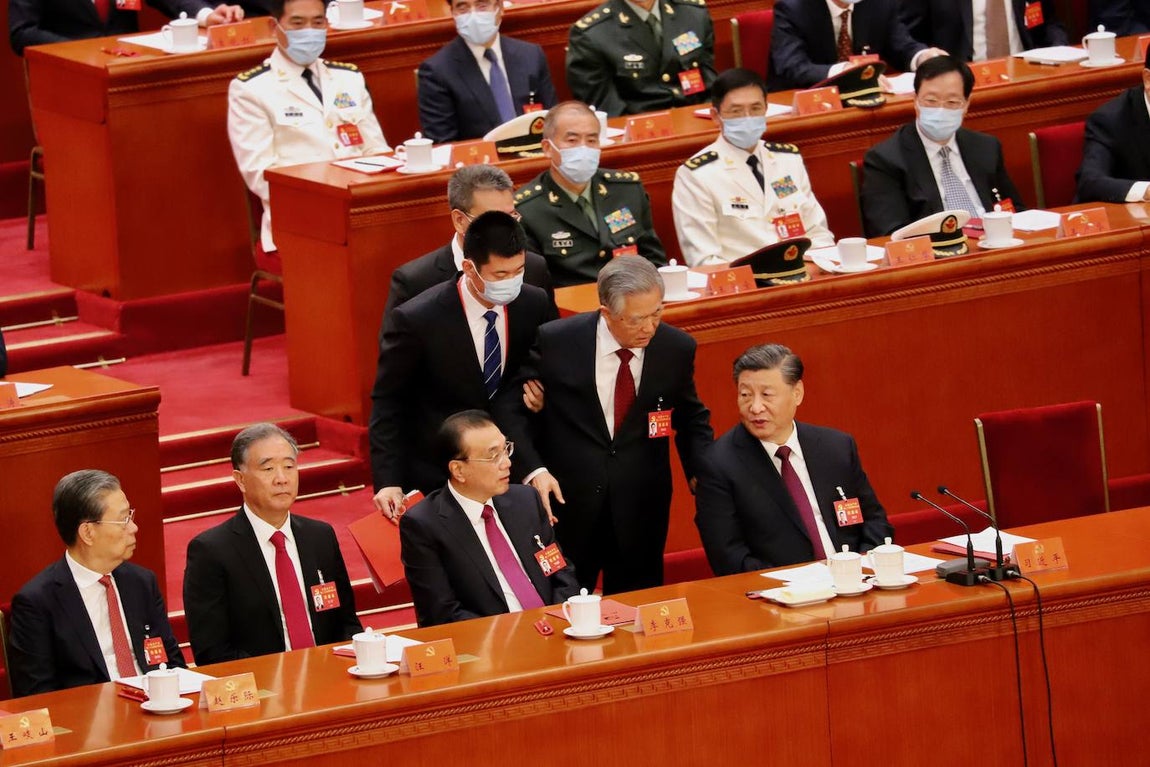 Finalmente, no le queda más remedio que marcharse, pero le dice algo a Xi Jinping, quien le contesta sin apenas mirarle. Por el pliegue de la chaqueta, se ve que el bedel está tirando de él.