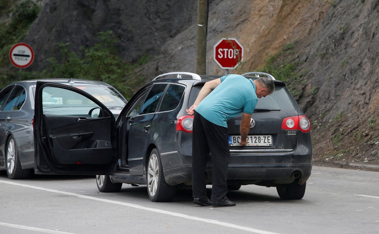 Un conductor quita una pegatina que cubre las marcas nacionales en las placas de su automóvil en el cruce fronterizo de Jarinje, Kosovo