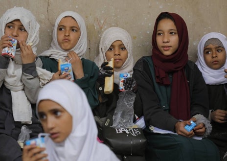 Imagen secundaria 1 - Campamento de desplazados en Yemen, al que la ONG lleva depósitos de agua, el bien más escaso del país. Debajo, un grupo de niñas come su desayuno y otro niño del campo posa con los sacos de provisiones