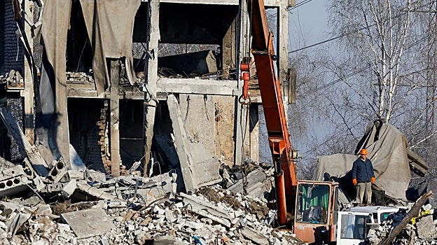 Trabajadores retiran los escombros de un edificio destruido que supuestamente era una escuela de formación profesional utilizada como alojamiento temporal para soldados rusos