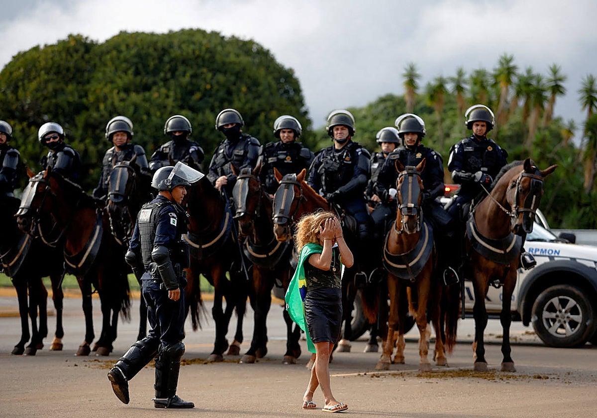 Una mujer se tapa los ojos con pena durante el desalojo de los campamenos bolsonaristas