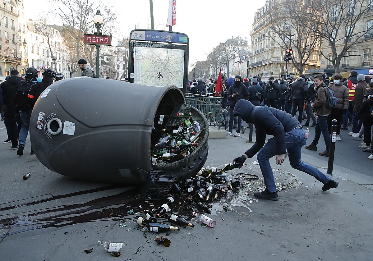 Un hombre derriba un contenedor de botellas durante la manifestación contra la reforma gubernamental del sistema de pensiones en París