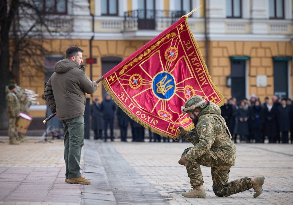 Zelenski extiende una bandera junto a un soldado en Kiev