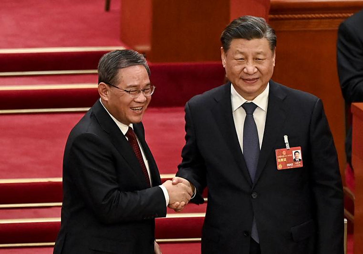 El presidente chino Xi Jinping (d) estrecha la mano del recién elegido primer ministro Li Qiang (i)