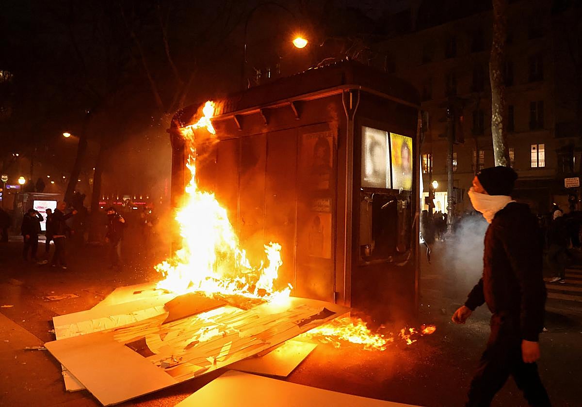 Un manifestante junto a un incendio callejero en las protestas de París contra la reforma de las pensiones