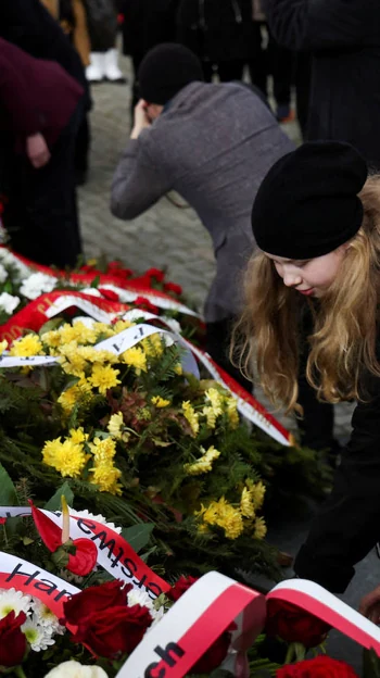 Several people lay flowers at the memorial dedicated to the victims of the Warsaw ghetto