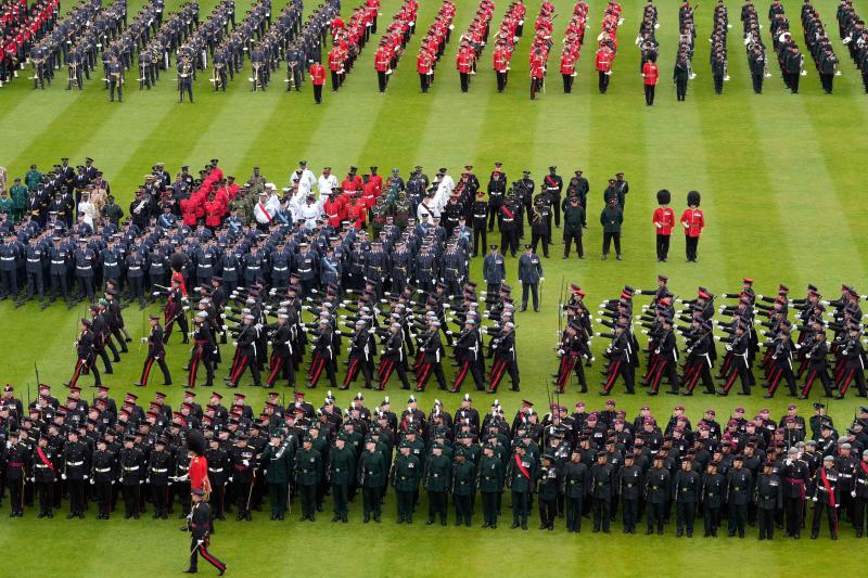 Miembros de las fuerzas armadas marchan sobre el césped frente al Palacio de Buckingham tras la coronación.