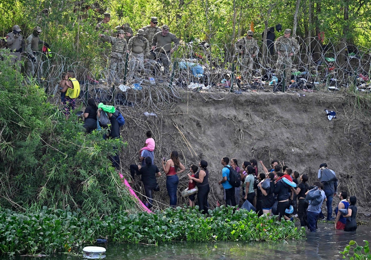 Los inmigrantes que cruzaron el río Bravo (Río Grande en EE.UU.) son detenidos por miembros de la Guardia Nacional de EE.UU. que colocan una valla de alambre de púas a lo largo del río en la frontera entre EE.UU. y México, visto desde Matamoros, estado de Tamaulupas, México,