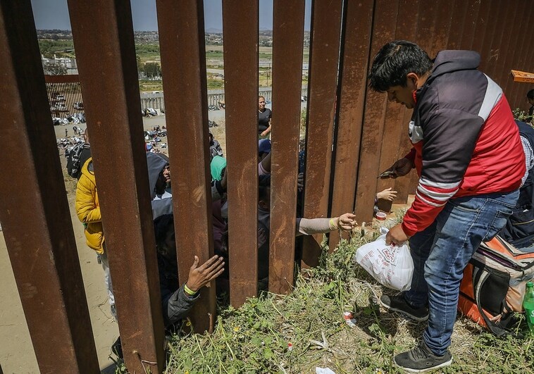 Repartidores de comida entregan pedidos a migrantes en el muro fronterizo de Tijuana (México)