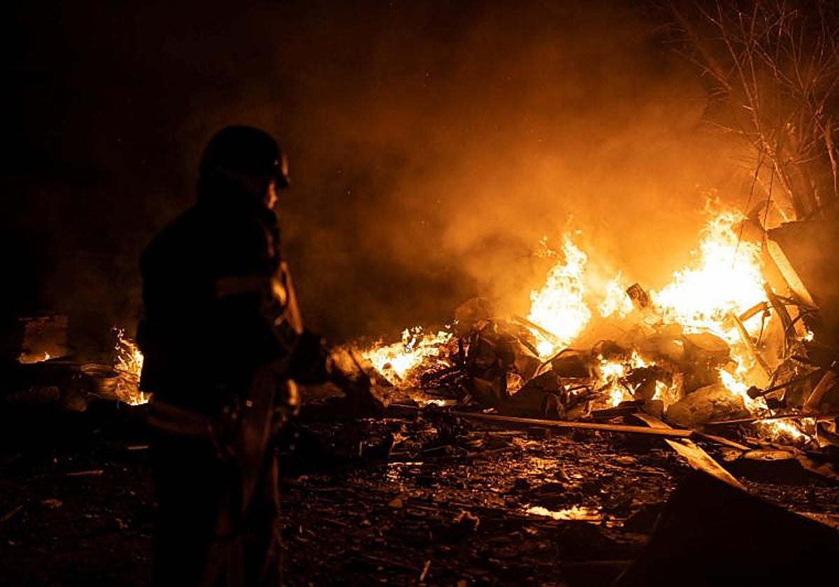 Un bombero acude aun parking en llamas por el lanzamiento de misiles rusos