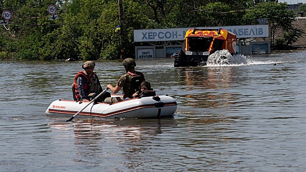 Las fuerzas de seguridad ucranianas transportan a los residentes locales en un bote durante una evacuación de un área inundada en Jerson