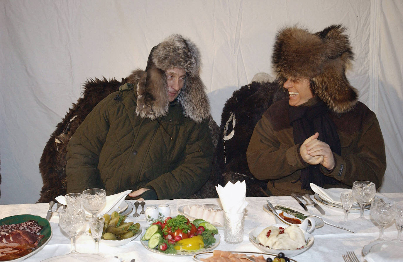 Silvio Berlusconi (derecha) y Vladimir Putin bromeando mientras se preparan para una cena informal a unos 120 km al noroeste de Moscú, en febrero de 2003