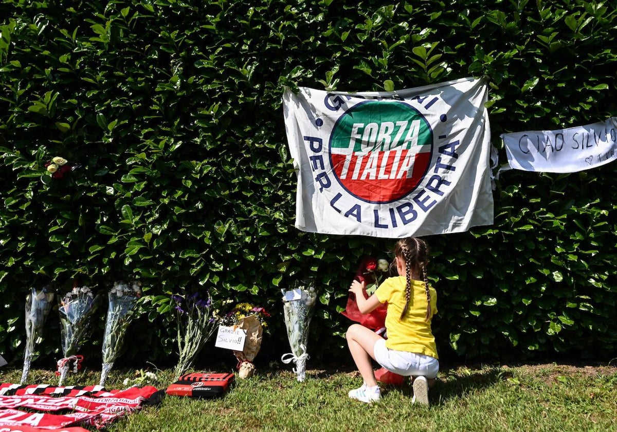 Una niña pone flores para rendir homenaje al empresario italiano y ex primer ministro Silvio Berlusconi, tras su muerte, fuera de su residencia Villa San Martino, en Arcore,