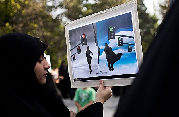 Una mujer iraní sostiene una pancarta durante una protesta para pedir el renacimiento del hiyab islámico y la castidad