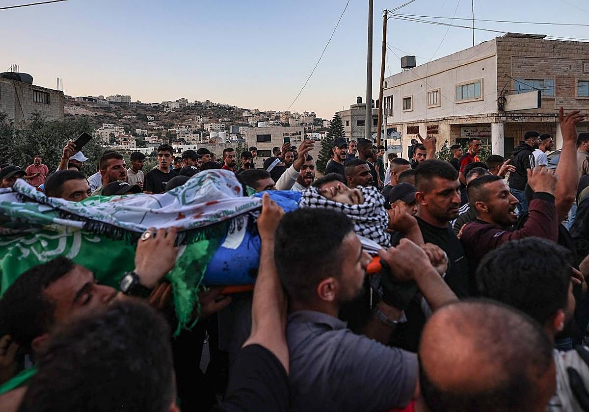 Varios hombres transportan el cuerpo de un palestino sospechoso de participar en un ataque anterior en el que murieron cuatro personas en el asentamiento israelí de Eli