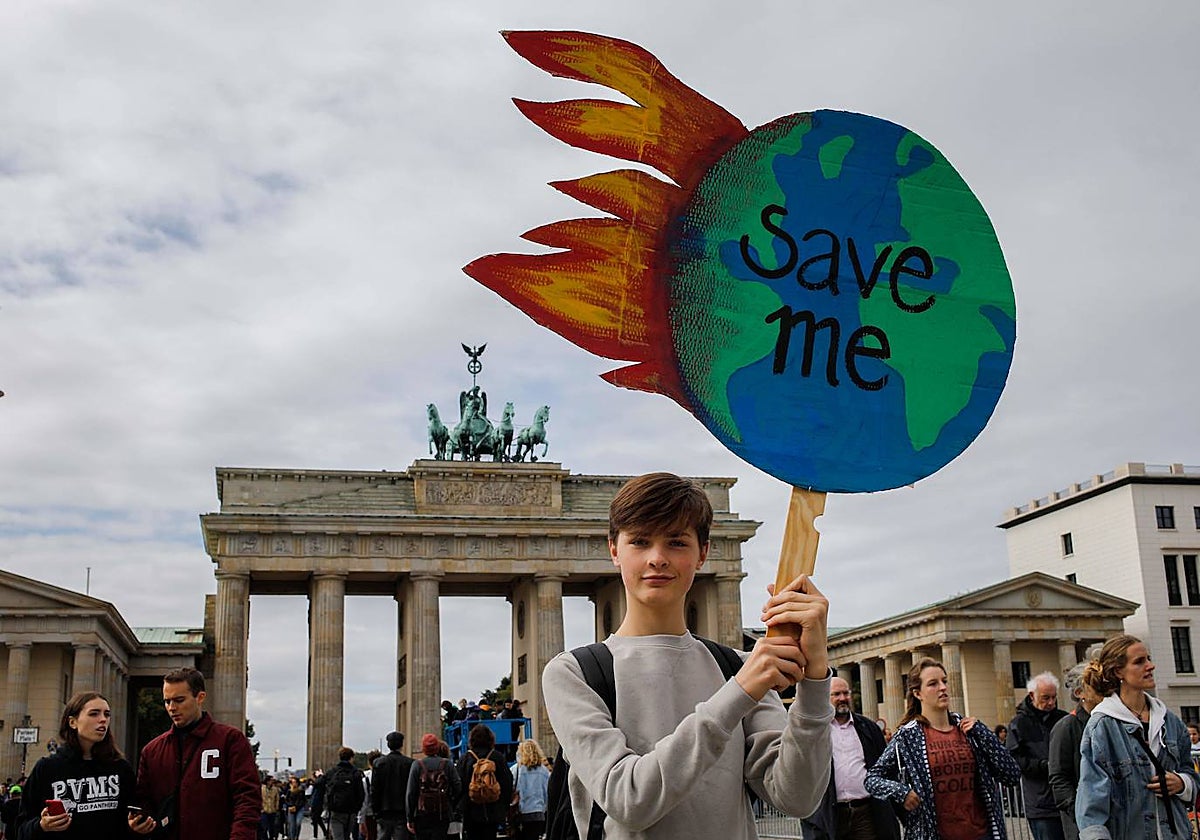 Un activista climático frente a la Puerta de Brandeburgo. En la pancarta se puede leer 'Sálvame'