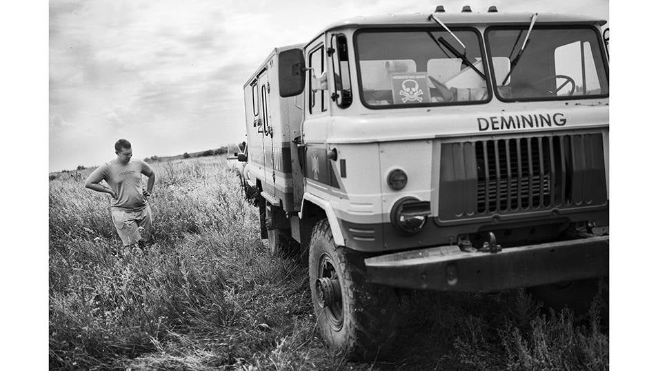 Un civil espera a que una unidad de desminado de los servicios de emergencia de Ucrania desactive una mina antitanque situada en un camino.