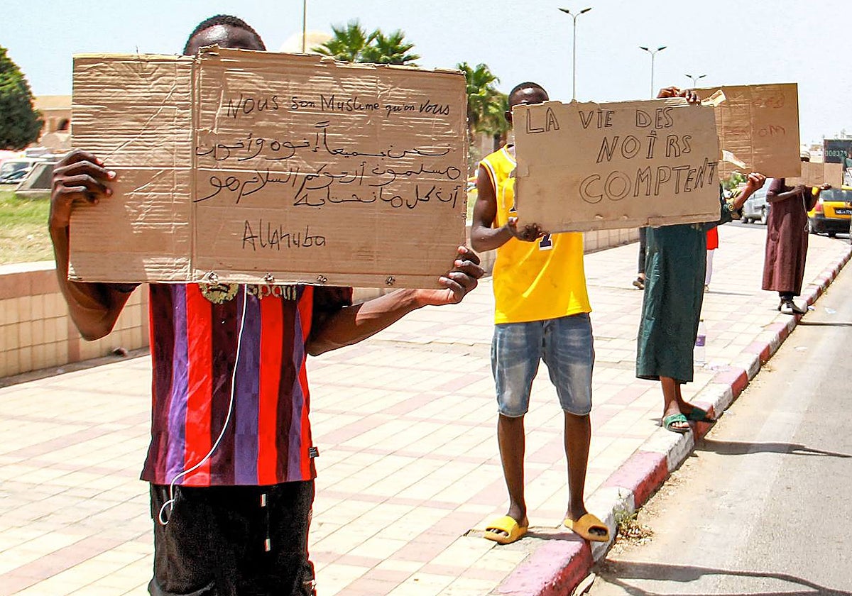 Un grupo de inmigrantes subsaharianos sostienen pancartas para denunciar las malas condiciones a las que se enfrentan en Túnez