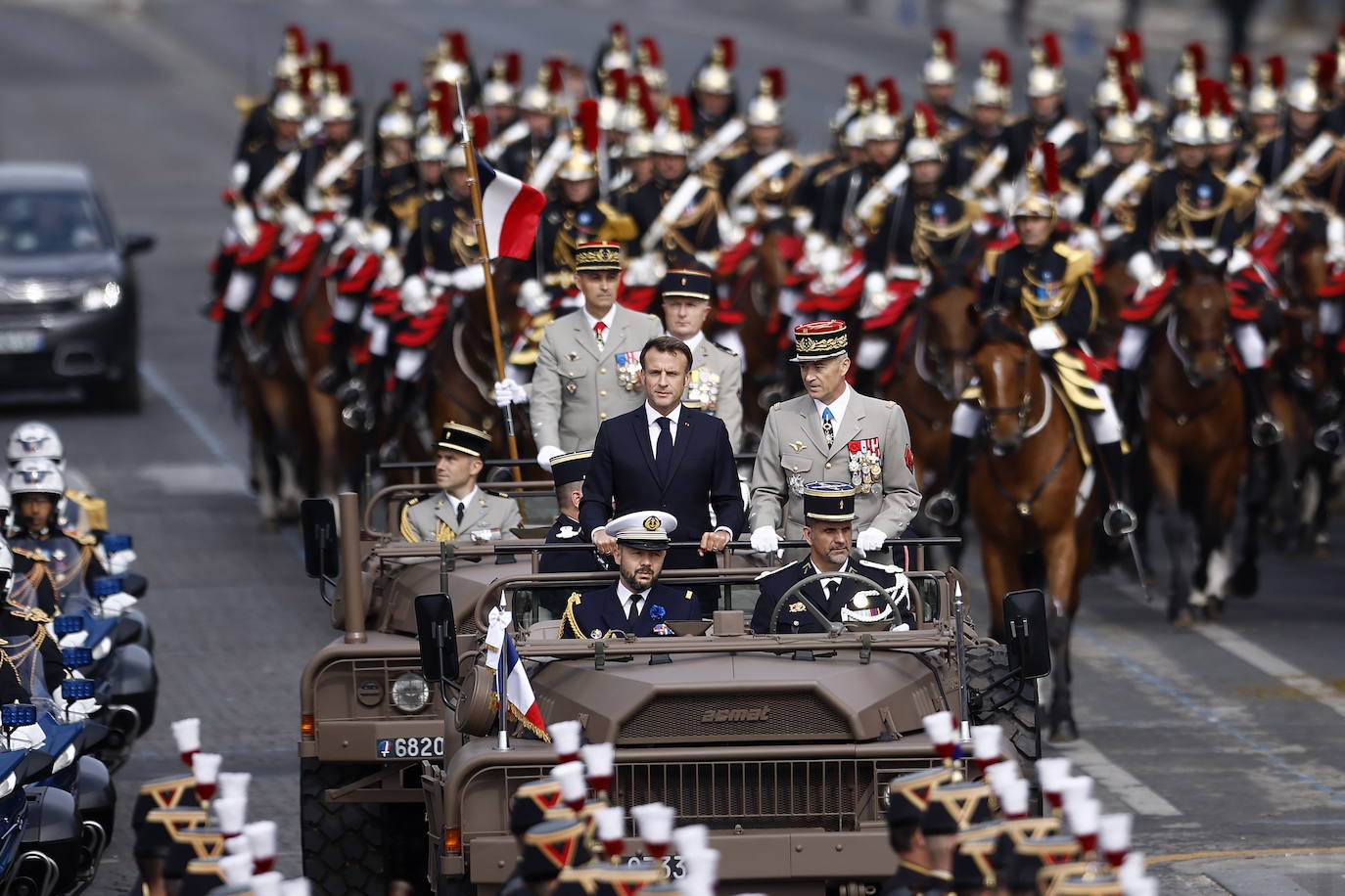 El presidente francés y el jefe del Estado Mayor de la Defensa, Thierry Burkhard, se paran en el auto de comando cuando llegan a los Campos Elíseos durante el desfile militar en París.