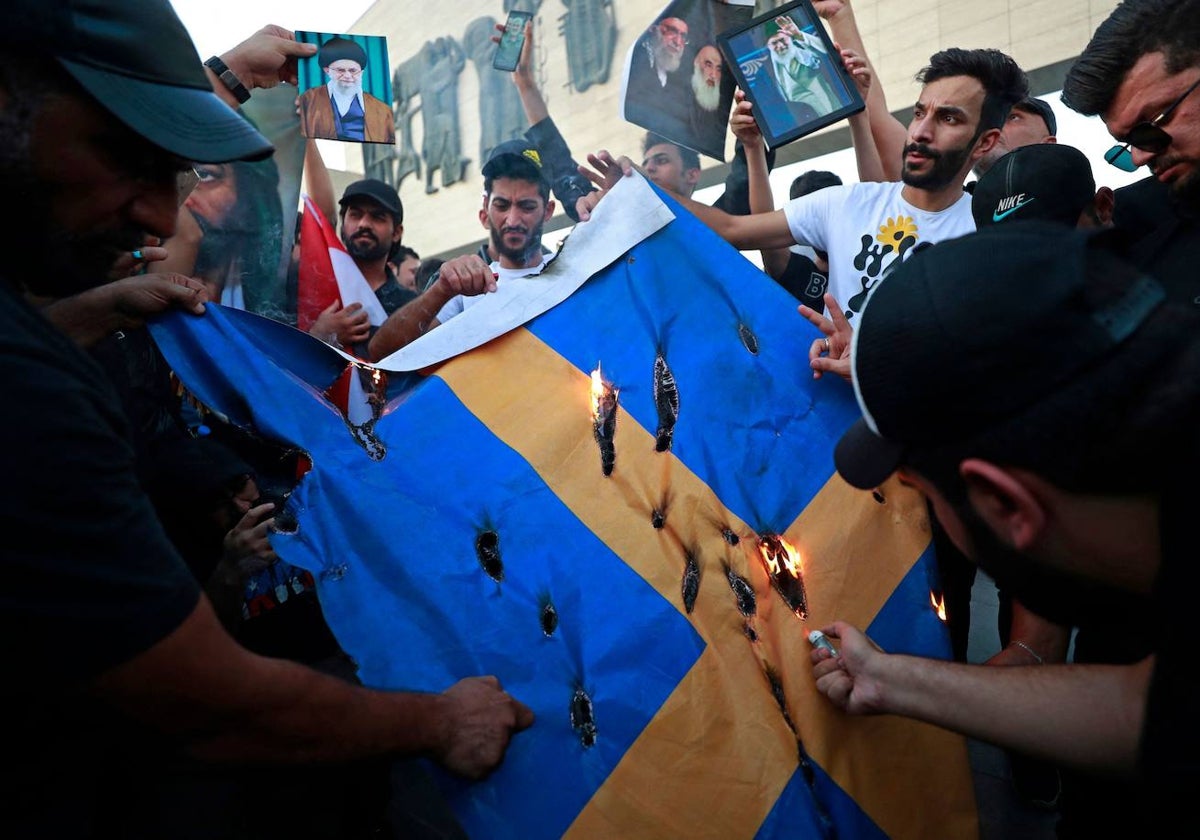 Los partidarios del ex grupo paramilitar Hashd al-Shaabi queman una bandera sueca durante una protesta en la plaza Tahrir de Bagdad