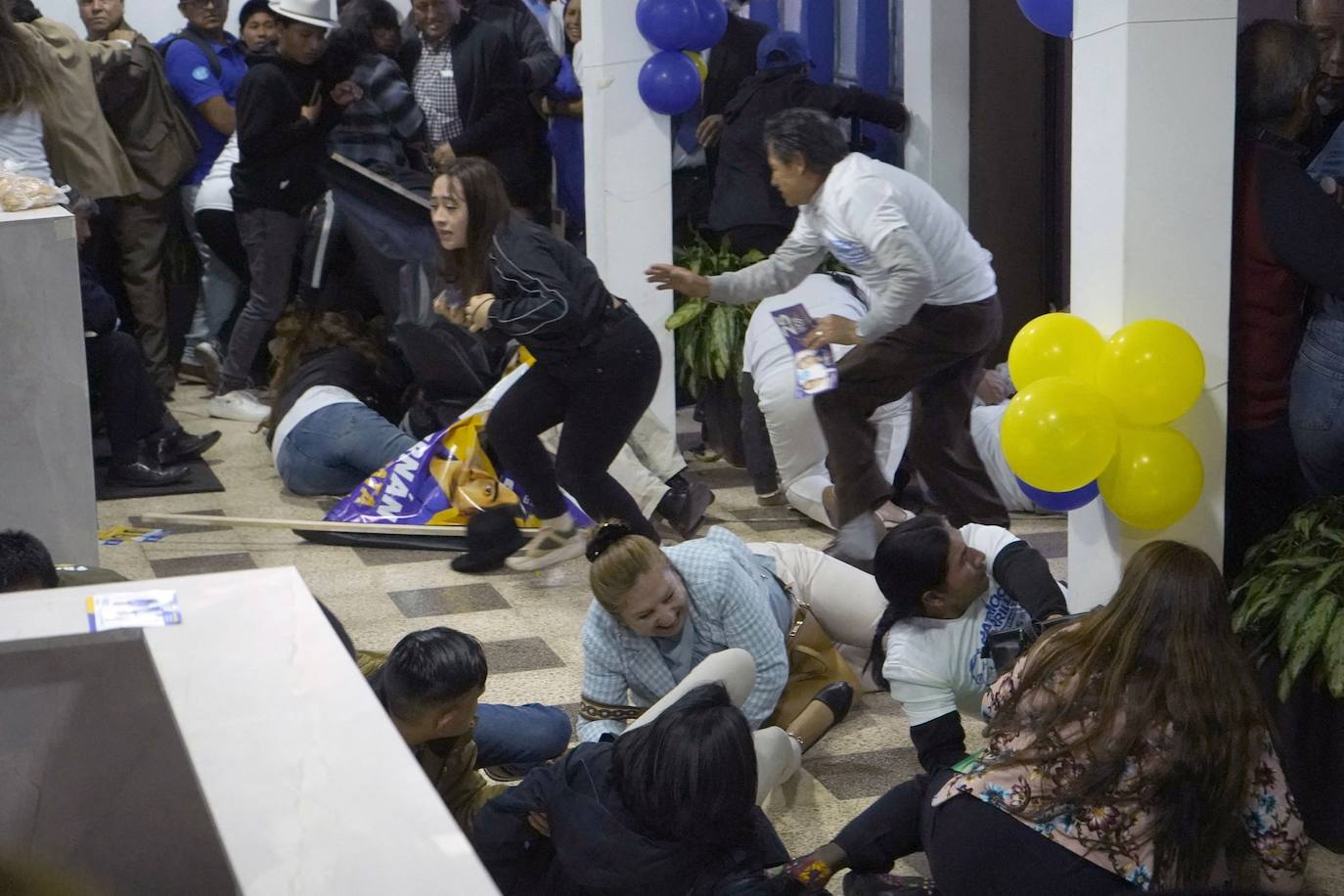 Personas se cubren tras los disparos al final de un mitin del candidato presidencial ecuatoriano Fernando Villavicencio en Quito, este 9 de agosto.