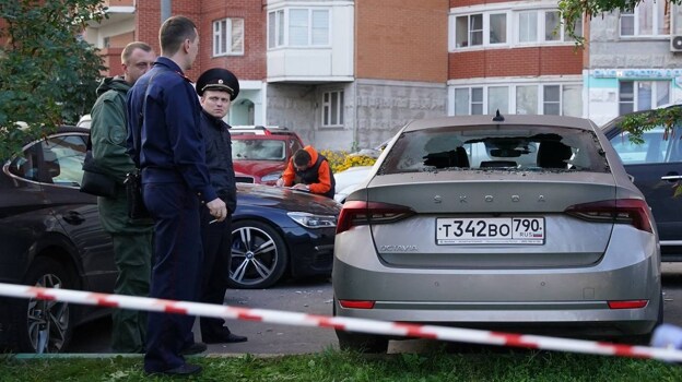 Los agentes del orden se encuentran junto a un automóvil dañado tras un ataque con drones en Krasnogorsk