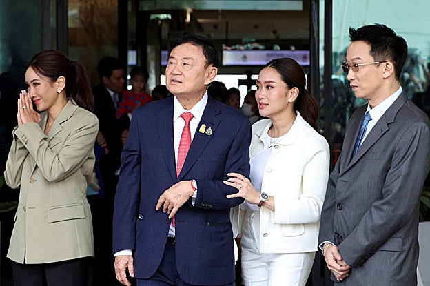 Thaksin Shinawatra camina con su hijo Panthongtae Shinawatra y sus hijas Paetongtarn Shinawatra y Pintongtha Kunakornwong en el aeropuerto Don Mueang de Bangkok