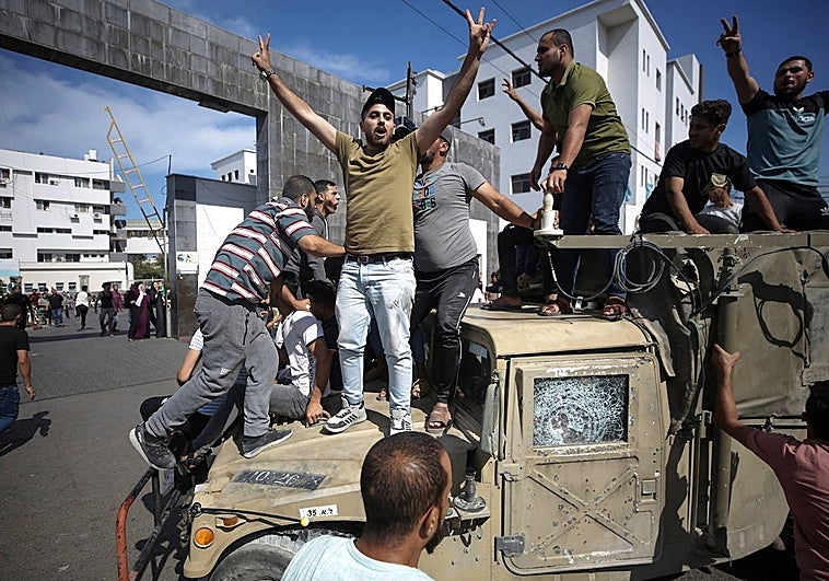 Un grupo de palestinos monta en un jeep militar israelí en las calles de Gaza durante el asalto de asentamientos israelíes
