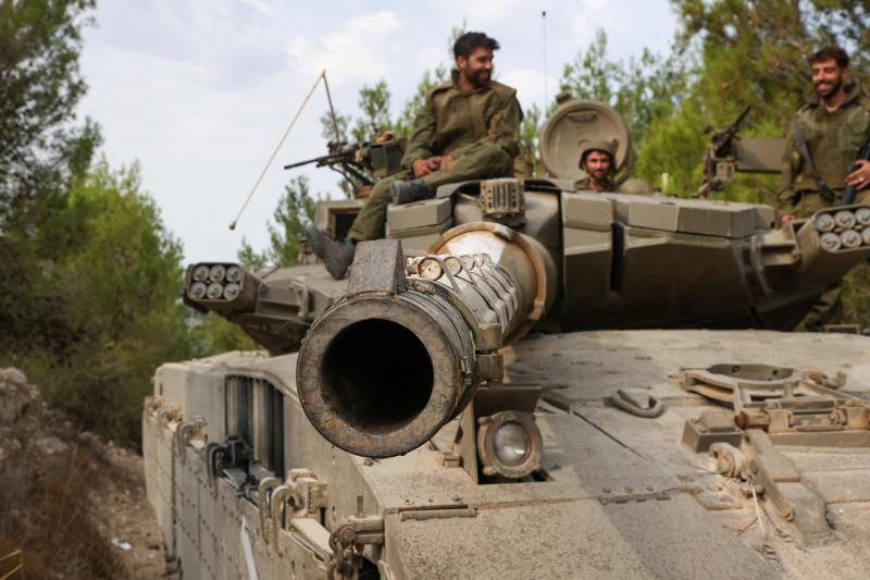 Soldados israelíes viajan en un tanque Merkava mientras se dirige a un lugar no revelado en el norte de Israel
