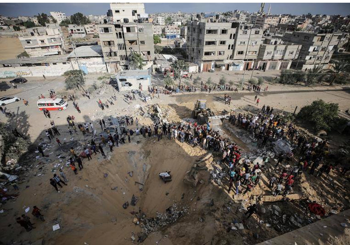 Palestinos buscan cadáveres y supervivientes entre los escombros de un edificio residencial derribado en un ataque aéreo israelí, en el campo de refugiados de Khan Younis, en el sur de la Franja de Gaza,