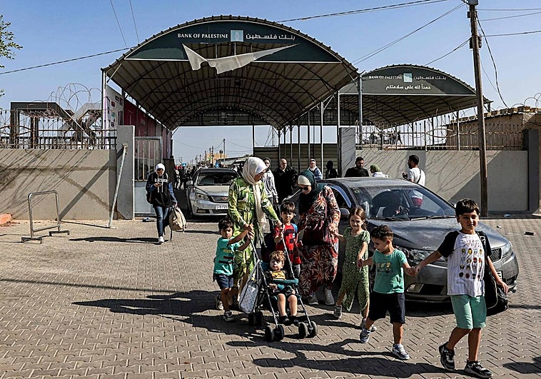 Varias personas entran en el paso fronterizo de Rafah, en el sur de la Franja de Gaza, antes de cruzar a Egipto